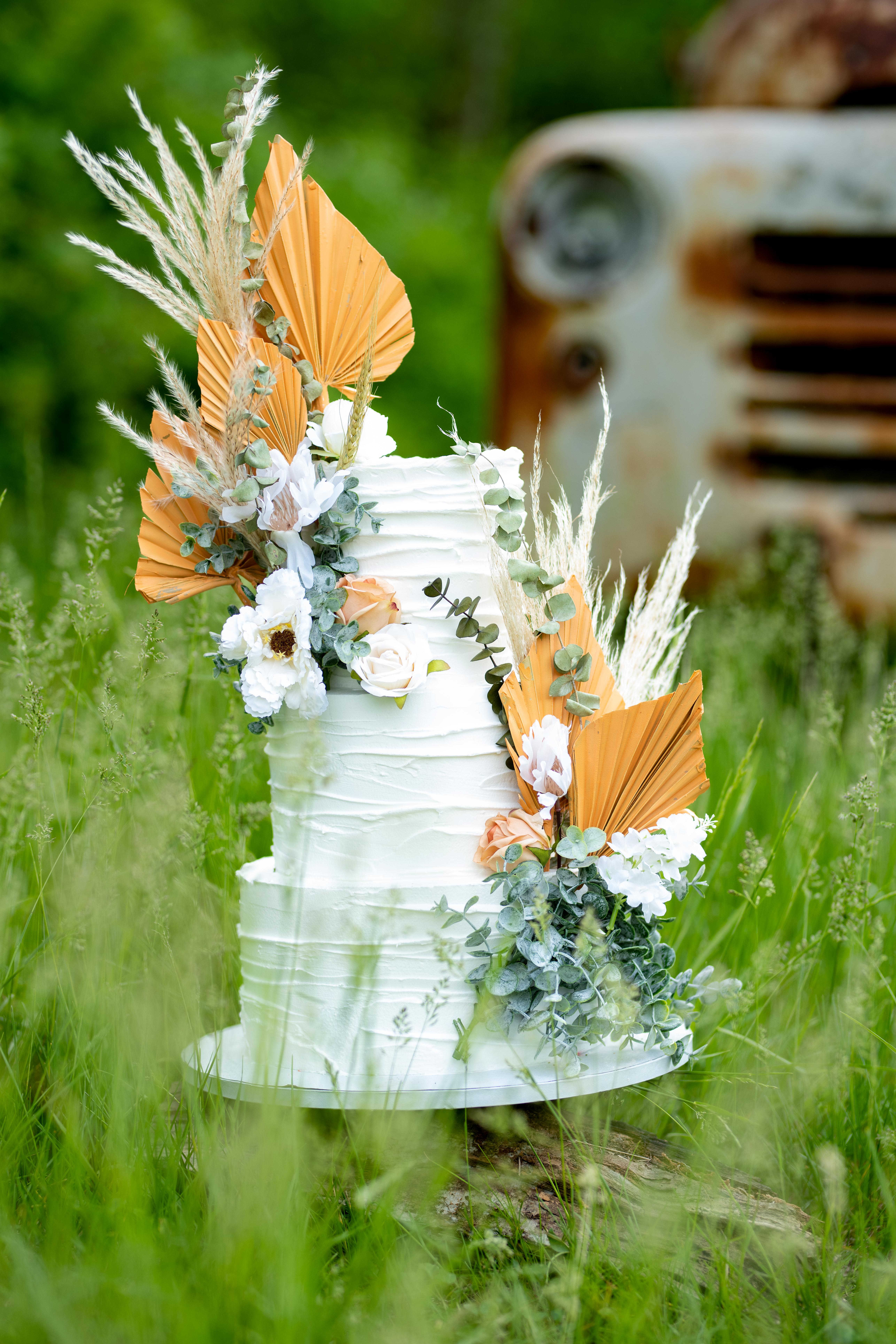 Large luxury wedding cake on a background of a flowering arch in the style  of boho. Wedding dessert under the light of evening light bulbs. Wedding  decor. Stock Photo | Adobe Stock